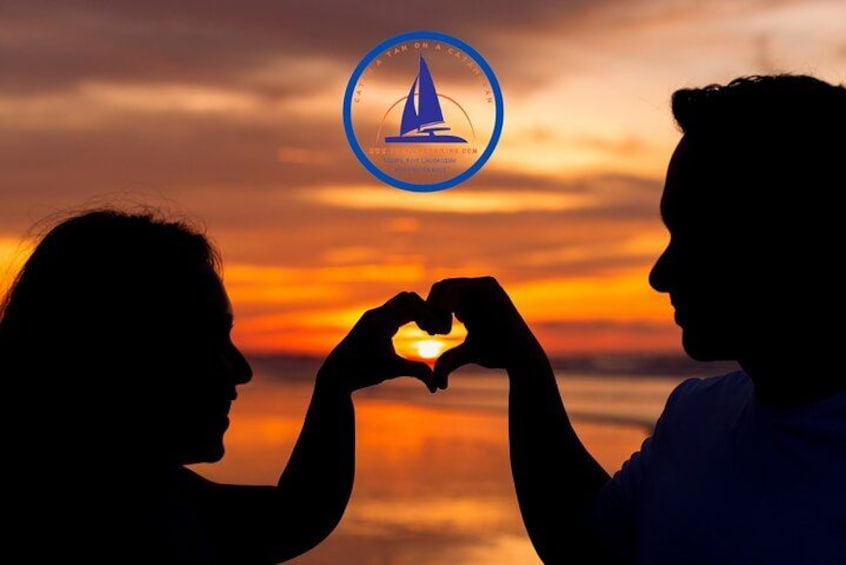 Dos siluetas forman un corazón con las manos al atardecer. 1