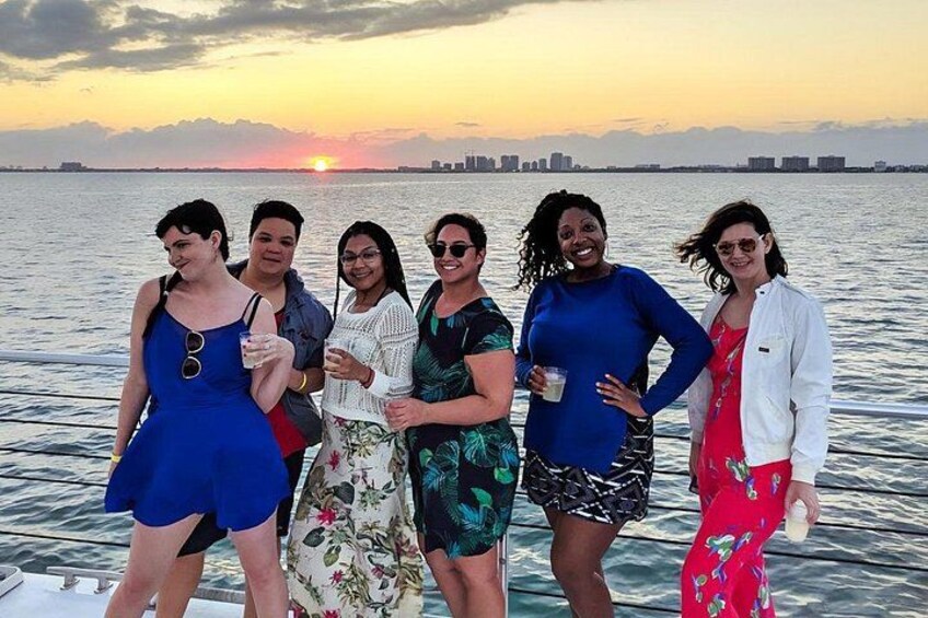 A group of people on a boat with a sunset in the background. 3
