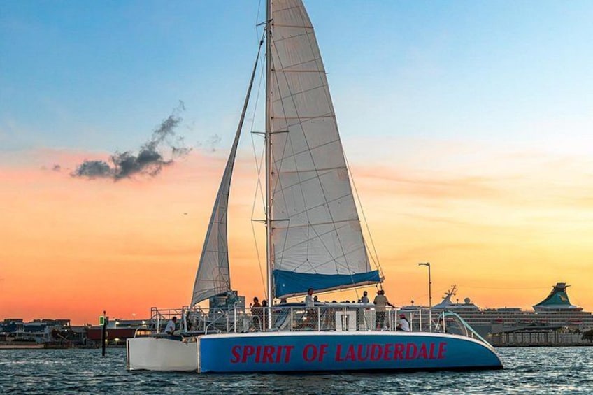 Un voilier baptisé « Spirit of Lauderdale », à la coque bleue et aux voiles blanches, était amarré à un quai, avec un coucher de soleil en toile de fond. 3