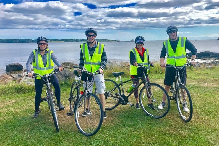 Four people with bicycles near a lake, wearing safety vests. 3