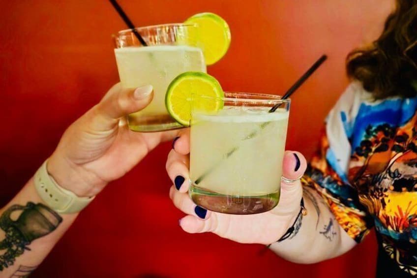 Two people holding glasses with drinks, one with a lime slice. 1