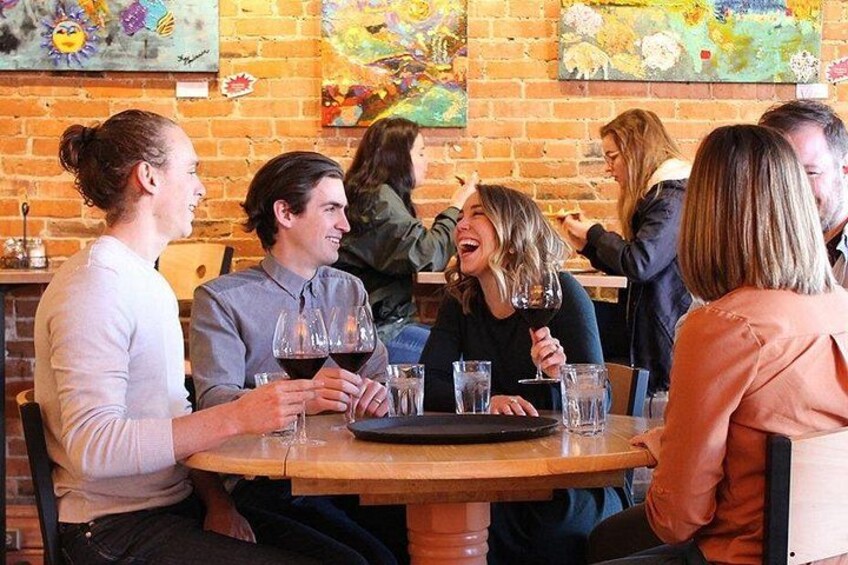 A group of people seated at a round table in a restaurant with brick walls and colorful artwork. 3