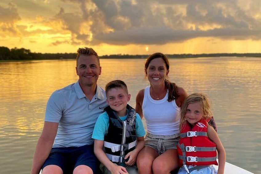 A family on a boat with a sunset in the background. 1