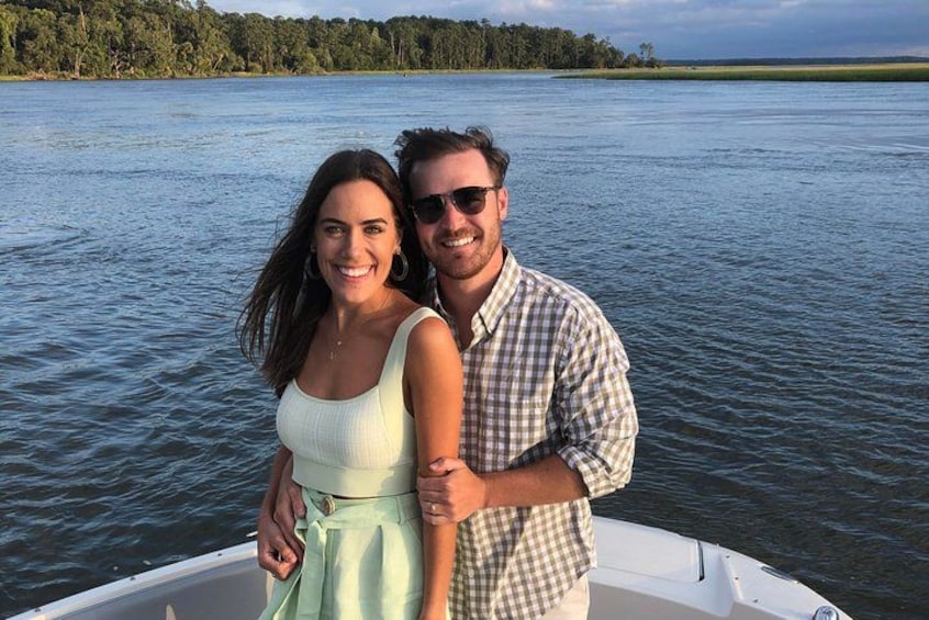 Two people on a boat on a calm lake with trees in the background. 5