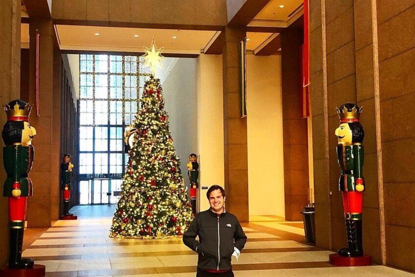 Una persona de pie en un pasillo con un árbol de Navidad decorado y figuras de cascanueces. 2