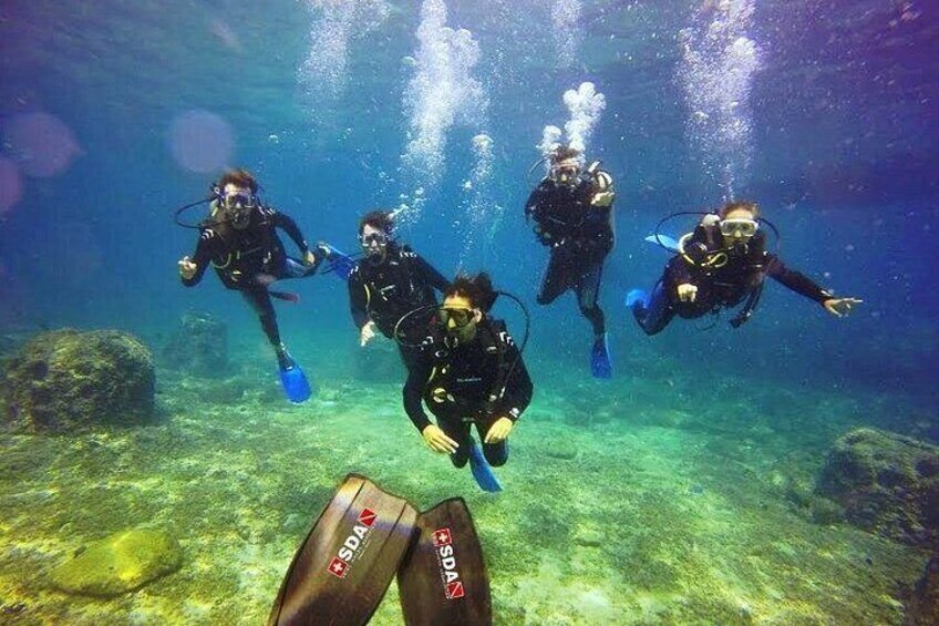 Four scuba divers underwater with fins and tanks. 4