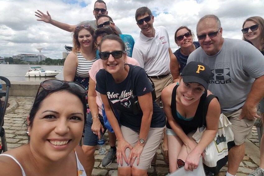 A group of people posing by a waterfront with a boat in the background. 2