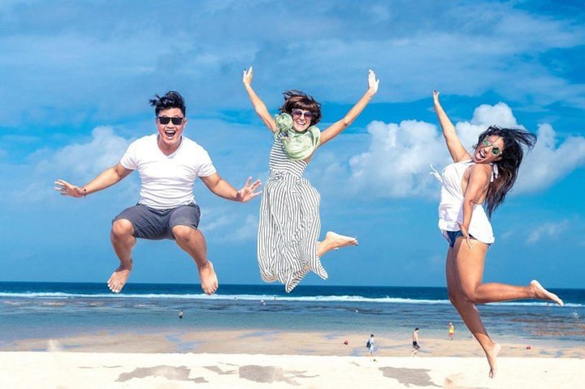 Tres personas saltando en una playa con el océano al fondo. 1