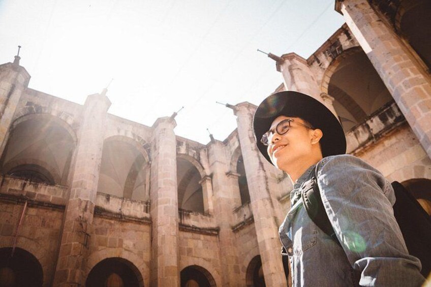 Una persona de pie frente a un antiguo edificio de piedra con arcos. 2