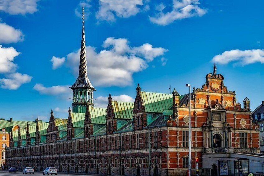 A historic building with a tall spire, ornate architecture, and a green roof. 2