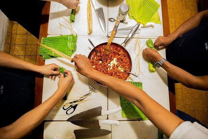 Un gruppo di persone che prepara cibo attorno a una pentola. 2