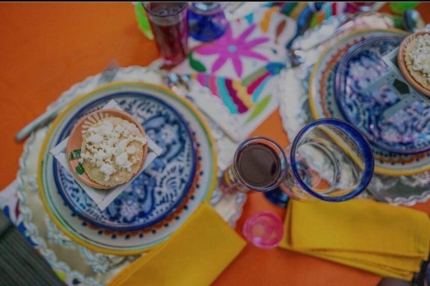Un tavolo con un piatto di cibo, un bicchiere di liquido scuro e una tovaglia colorata. 4