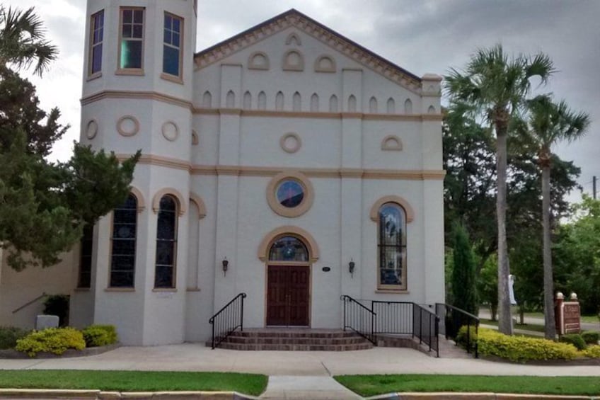 A white church with a bell tower, arched windows, and a central door. 4