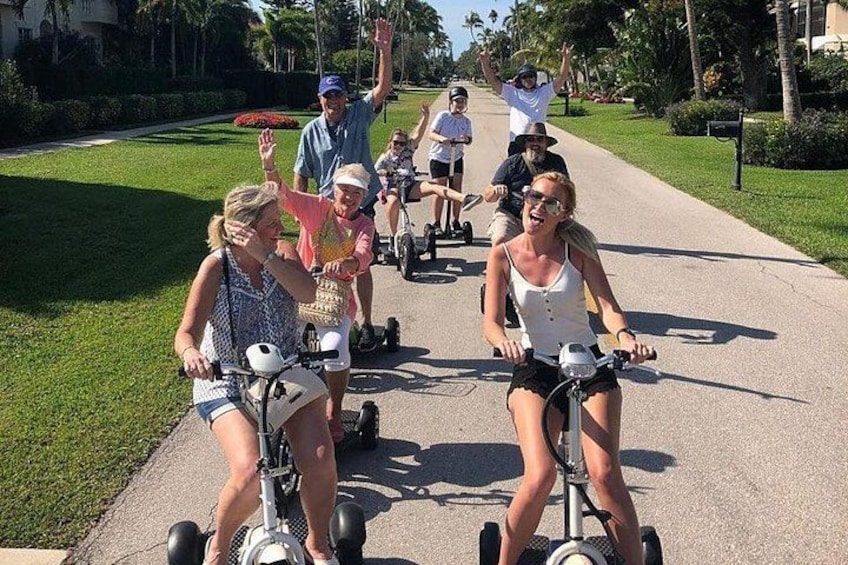 Un grupo de personas paseando en patinetes eléctricos por un sendero pavimentado en un parque. 1