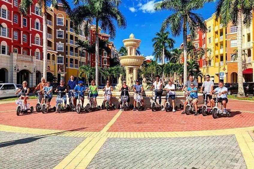 Un grupo de personas en segways en una plaza con palmeras y edificios coloridos. 5