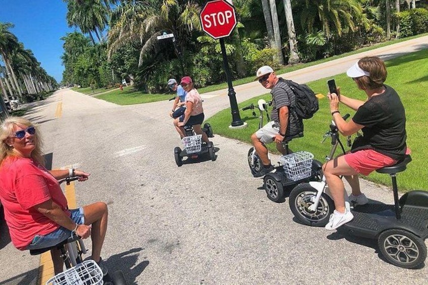 Tres personas en segways, una señal de parada y una calle bordeada de palmeras. 4