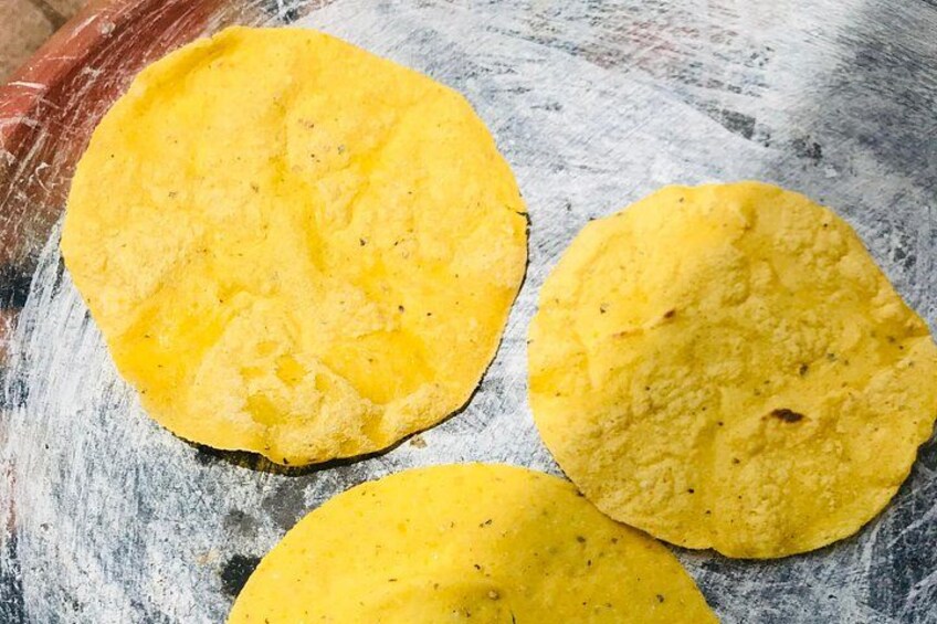 Three yellow tortillas on a floured surface. 4