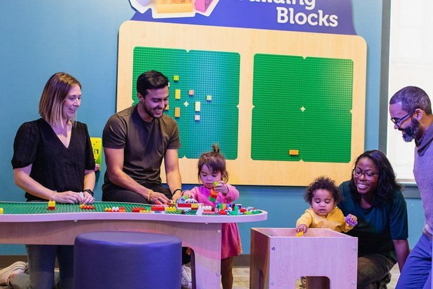 Un grupo de personas participan en una actividad de construcción usando bloques de colores en una mesa. 2