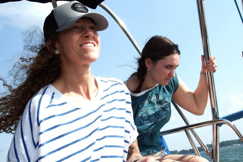 Twee personen in een boot, één met een geruite shirt en de ander in een blauwe top, met water en een heldere lucht op de achtergrond. 5