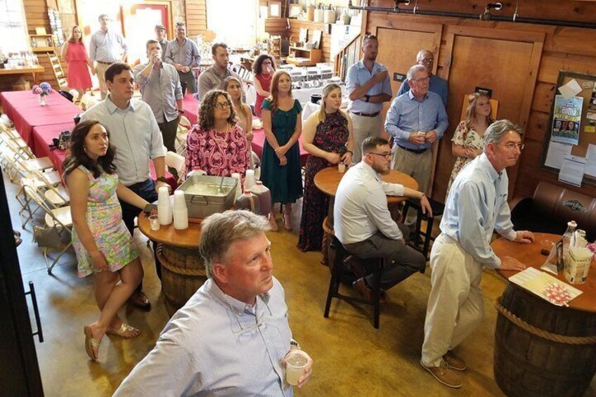 A group of people in a rustic interior with wooden tables and barrels, suggesting a social gathering or event. 2