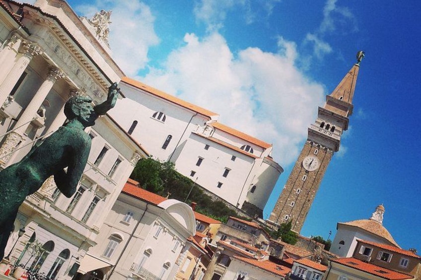 Un edificio histórico con una torre del reloj y una estatua en su fachada. 5