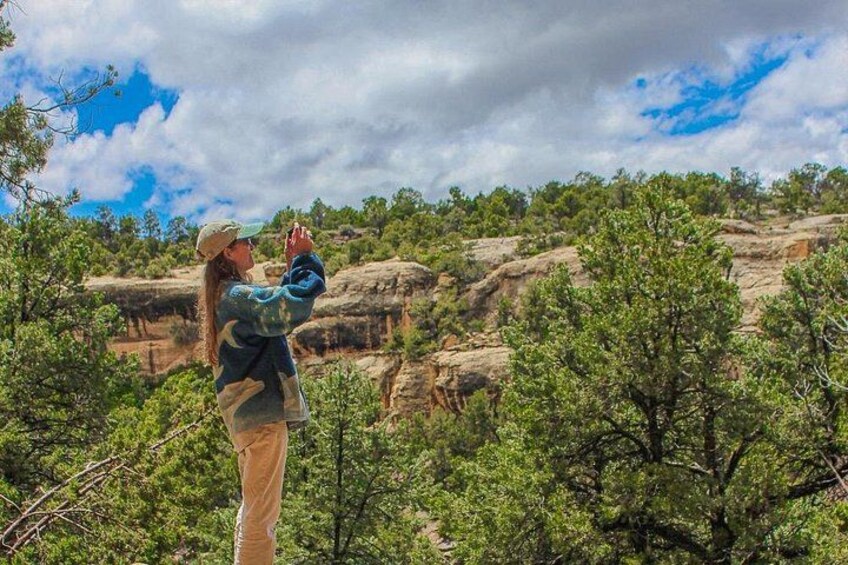A person taking a photograph of a rocky landscape with trees. 4