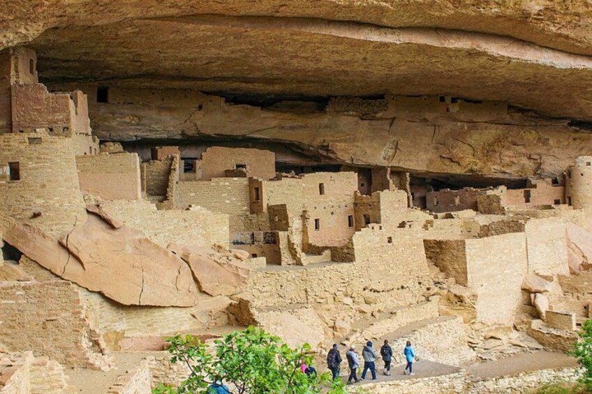 Ancient cliff dwellings with people walking in front. 2