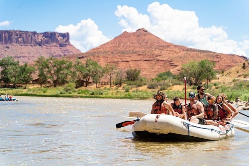 A group of people rafting on a river with a mountainous landscape in the background. 4