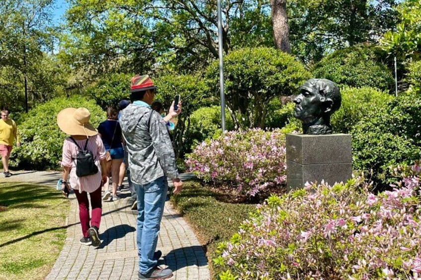 A statue in a park with people walking around it. 5