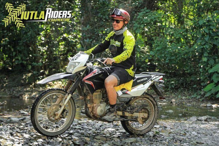 A person riding a motorcycle on a rocky path surrounded by greenery. 2