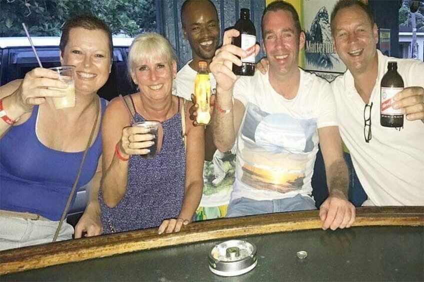A group of people at a bar with bottles and glasses. 1