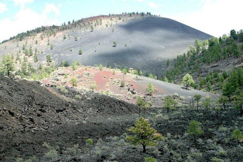 Un paisaje volcánico con una colina yerma, vegetación escasa y cielo despejado. 2