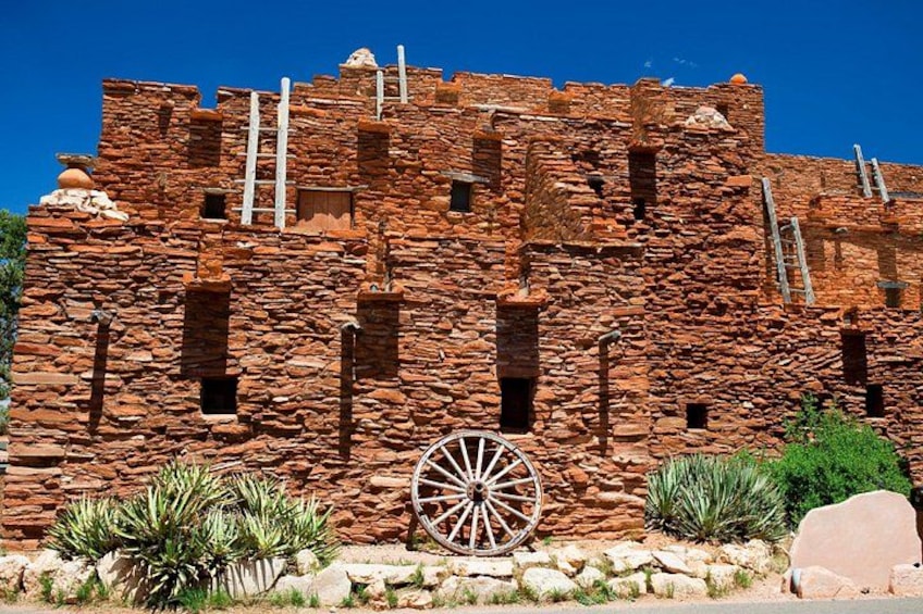 Un edificio histórico de piedra con una gran rueda en primer plano. 2