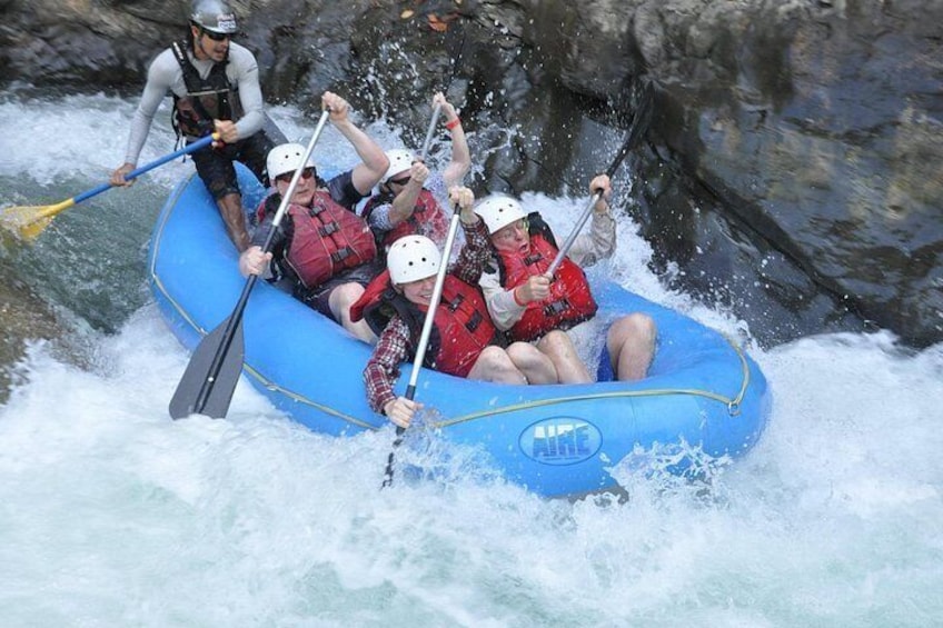 Een groep mensen in een blauwe opblaasboot die een rivier afvaart. 5