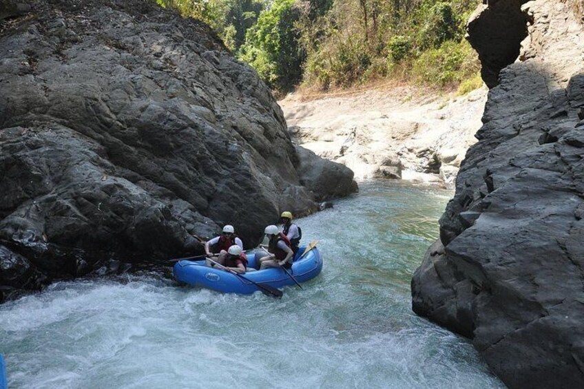 Een groep mensen die op een raft een rivier afdaalt, omgeven door rotsachtige kliffen. 2
