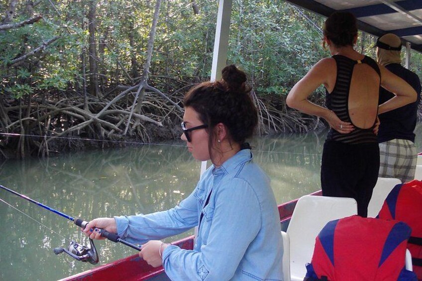 A person fishing on a boat with a mangrove background. 5