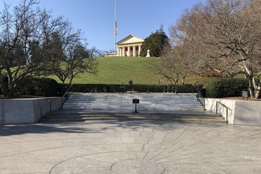 A grand building with steps leading up to it, surrounded by trees and a flag. 4