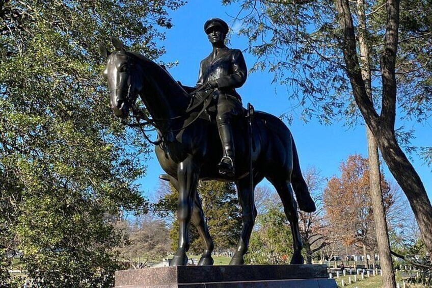 Una estatua de un hombre montado a caballo en un parque con árboles y cielo despejado. 5