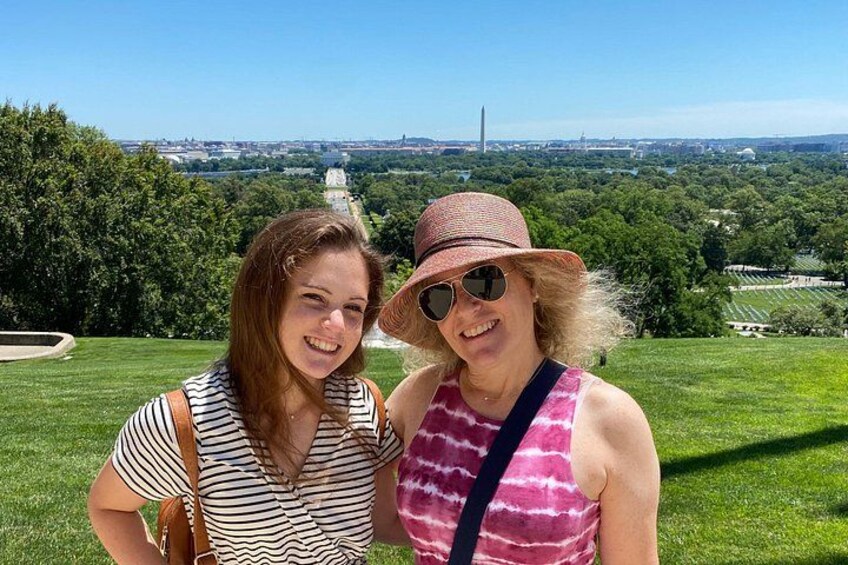 Two people standing on a grassy hill with a cityscape in the background. 5
