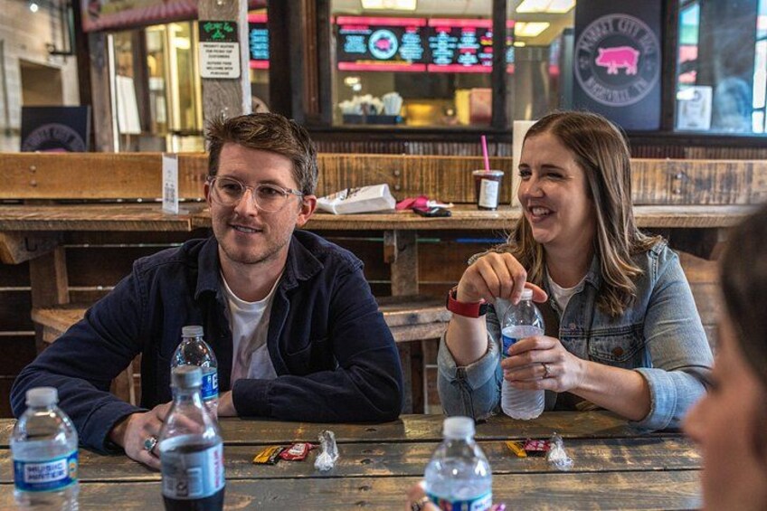 Two people sitting at a wooden table with water bottles and a menu in a restaurant. 5