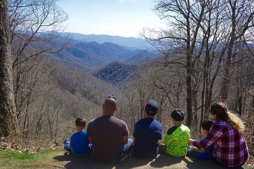 A family of five sitting on a hillside overlooking a valley. 3
