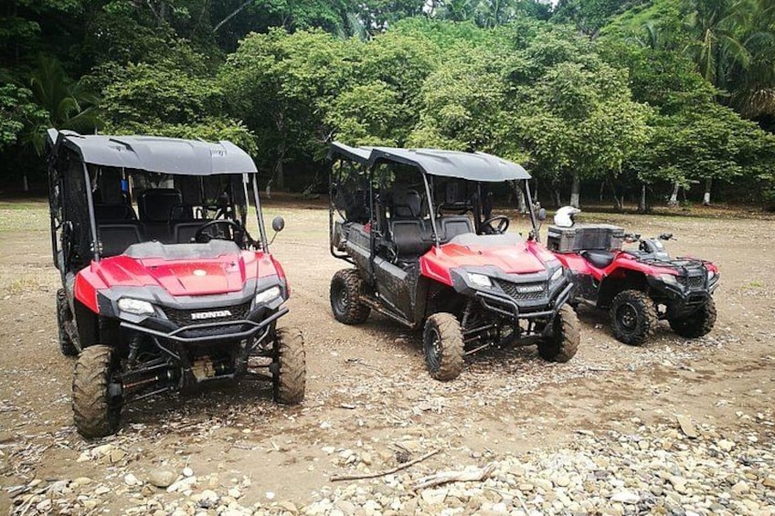 Three off-road vehicles parked on a gravel surface with trees in the background. 2