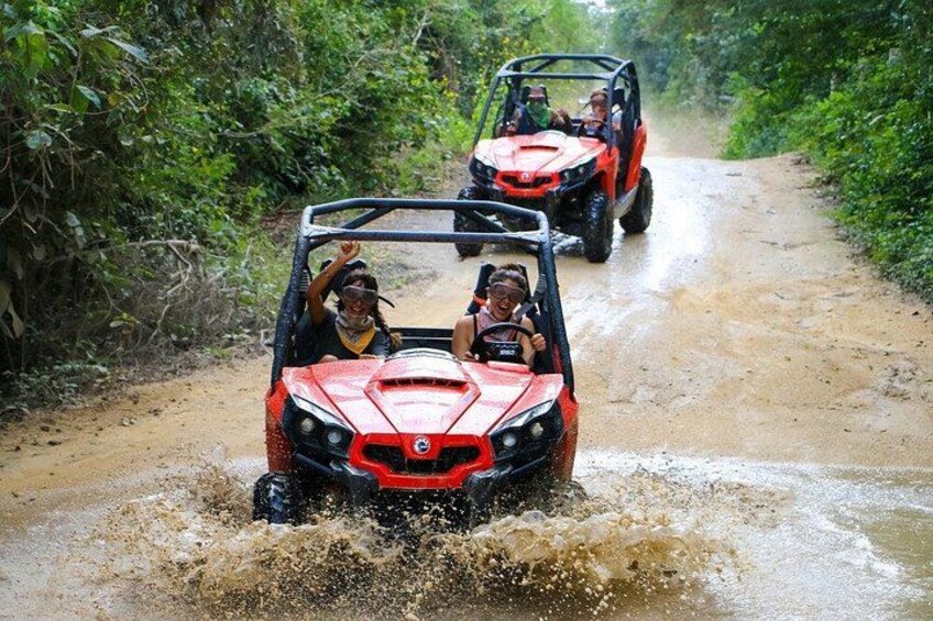 Two off-road vehicles driving on a muddy path surrounded by dense vegetation. 4