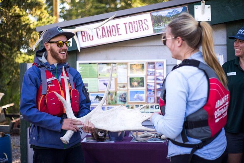 A person holding a large white object, possibly a canoe, at a booth labeled 'Big Canoe Tours.' 4