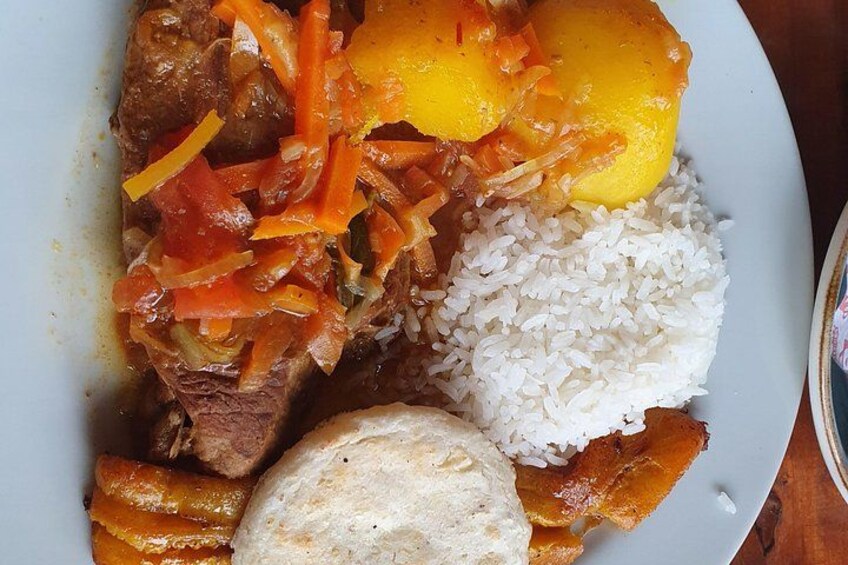 A plate with white rice, a piece of meat, a yellow fruit, and a slice of bread. 2