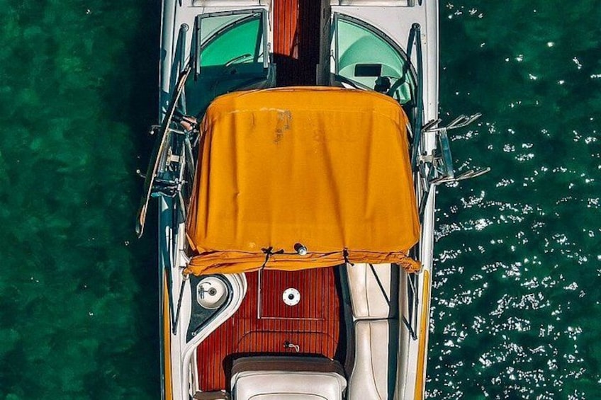 A boat with a yellow cover on the deck, a steering wheel, and a wake behind it. 3