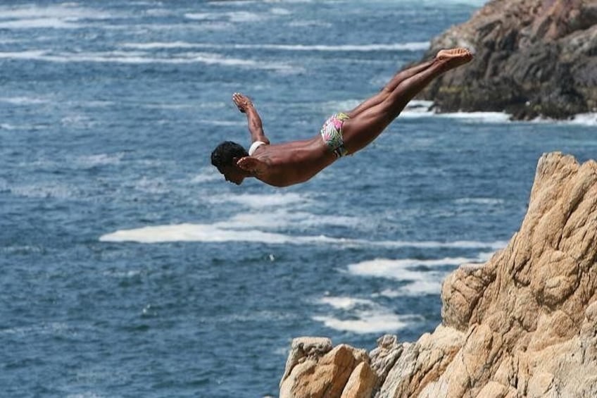 A person diving off a rocky cliff into the ocean. 3