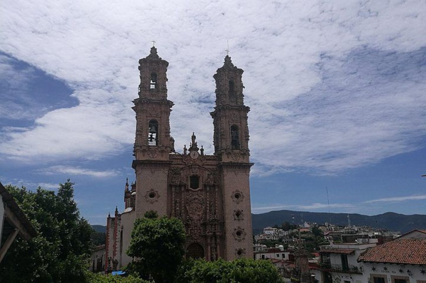 A historic church with two bell towers, surrounded by trees and buildings. 4