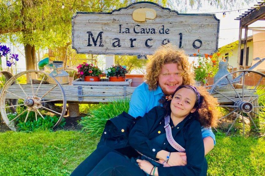 A wooden sign with 'La Cava de Marcelo' written on it, surrounded by greenery and a vintage cart. 2