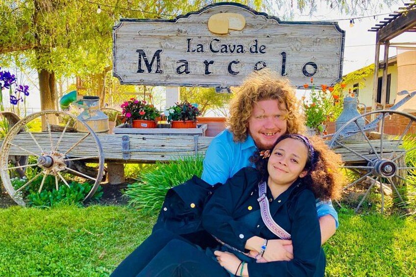 A wooden sign with 'La Cava de Marcelo' written on it, surrounded by greenery and a vintage bicycle. 2